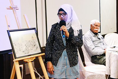 Palestinian student explains the meaning of her drawing made for the Open Day to the participants